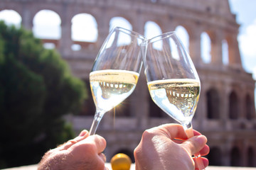 two hands hold a glass of champagne against the backdrop of the Coliseum. Christmas concept...