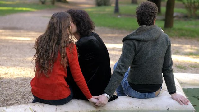 women kissing while man covertly flirting with one of them.threesome, infidelity