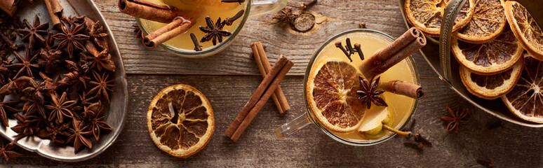 top view of warm pear mulled wine with spices and dried citrus on wooden table, panoramic shot
