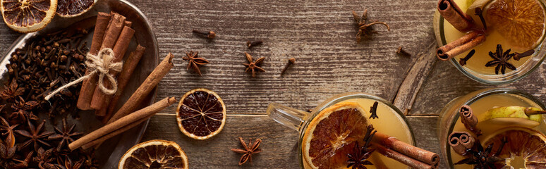 top view of warm pear mulled wine with spices and dried citrus on wooden rustic table, panoramic shot