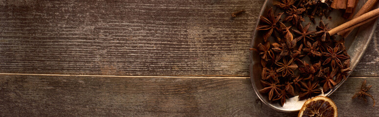 top view of cinnamon sticks, anise and dried citrus fruit on wooden rustic table, panoramic shot