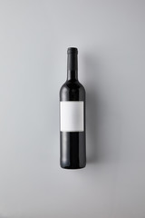 top view of bottle with red wine and blank label on white background