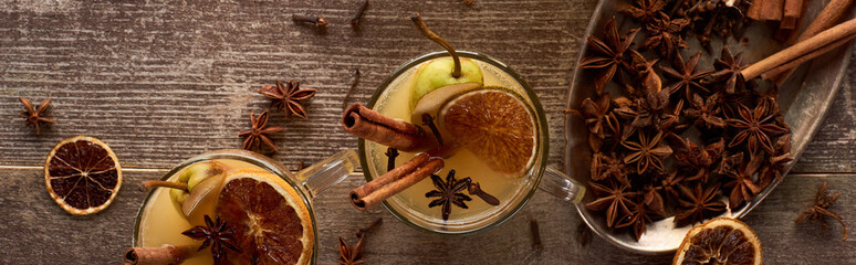 top view of traditional warm pear mulled wine with spices and dried citrus on wooden rustic table, panoramic shot