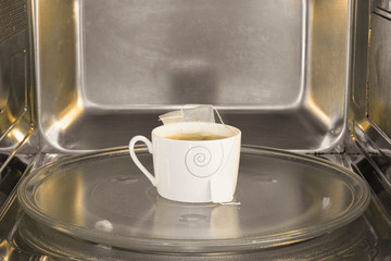 Tea cup inside the microwave. Warming the tea on the microwave.