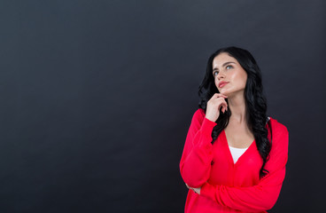 Young woman in a thoughtful pose on a black background