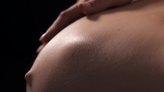 Close-up of pregnant woman with baby moving and kicking inside belly, future mother carefully touch tummy and playing with her baby. Last trimester of pregnancy