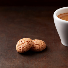 Amaretti (Italian biscuits) and a cup of coffee on dark wooden background. Close up. 