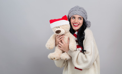 Obraz premium Young woman holding a teddy bear on a gray background
