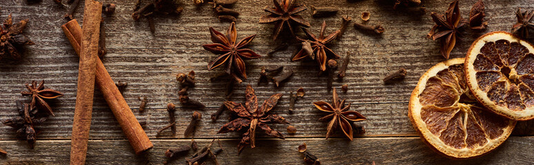top view of cinnamon sticks, anise and dried citrus fruit on wooden rustic table, panoramic shot