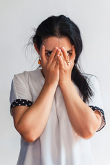 Portrait of a cute female. Beautiful and young lady hiding her face and looking through hands. Facial expressions of attractive middle-eastern or Hispanic woman