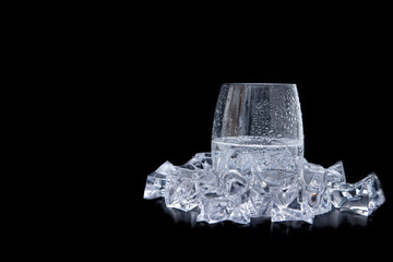 glass of water with ice and bubbles on black background