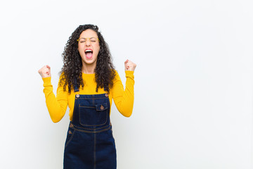 young pretty woman feeling happy, positive and successful, celebrating victory, achievements or...