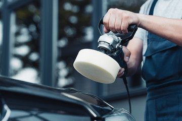 cropped view of car cleaner polishing car with buffer machine