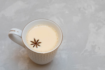Cup of masala tea (chai) with star anise on grey background. Image with copy space