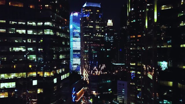 JAKARTA, Indonesia - October 07, 2019: Beautiful aerial view of modern skyscrapers exterior with night lights. Shot in 4k resolution from a drone flying forwards