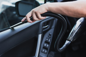 Naklejka premium cropped view of car cleaner vacuuming car door