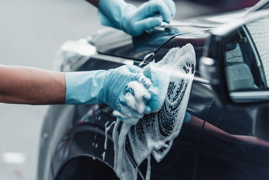 cropped view of car cleaner washing car with sponge and detergent