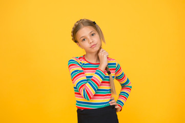 Little girl. Small child with cute braids hairstyle on yellow background. Child care concept....
