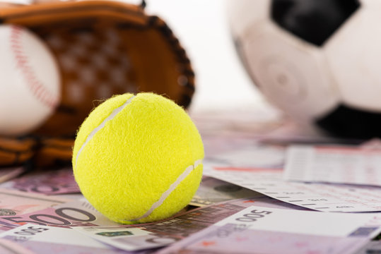 selective focus of tennis ball near soccer ball, baseball glove and ball on dollar and euro banknotes isolated on white, sports betting concept