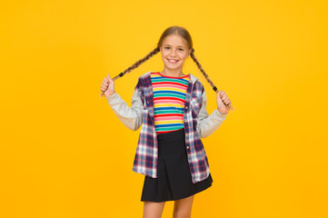 Preteen girl colorful clothes. Childrens shop store mall. Adorable girl beautiful face. Hairdresser salon. Little girl. Small child with cute braids hairstyle on yellow background. Child care concept