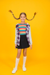 Adorable girl beautiful face. Hairdresser salon. Little girl. Small child with cute braids hairstyle on yellow background. Child care concept. Preteen girl colorful clothes. Childrens shop store mall