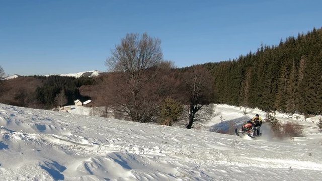 Sport yellow snowmobile jump in slow motion. Cloud of snow dust from under snowmobile tracks. Concept quick movement. Extreme sport background for any purposes