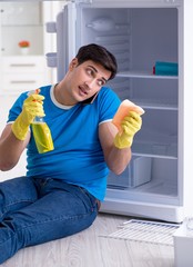 Fototapeta na wymiar Man cleaning fridge in hygiene concept