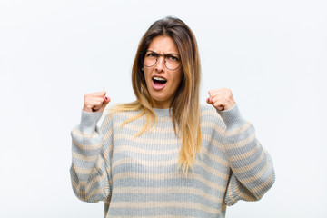 young pretty woman shouting aggressively with an angry expression or with fists clenched...