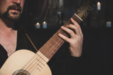 Adult man in historical suit playing vihuela....