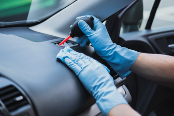 cropped view of car cleaner dusting ventilation holes with rubber air blower