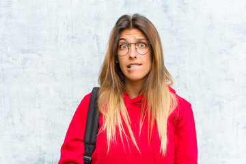 young pretty student feeling clueless, confused and uncertain about which option to pick, trying to...