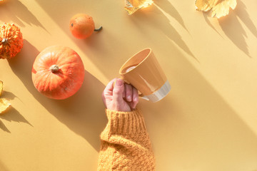  Top view with long shadows and copy-space. Yellow paper flat lay with female hand holding cup of...