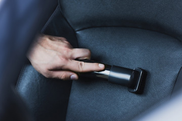 cropped view of car cleaner vacuuming car seat