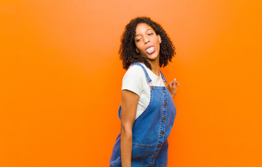 young pretty black woman with cheerful, carefree, rebellious attitude, joking and sticking tongue...