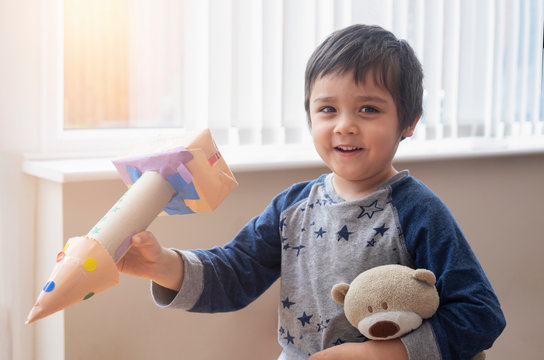 Cute little boy playing with spaceship, Happy child holding toy rocket and teddy bear toy, Toddler creativity, Concept for diy, art and craft in a classroom or Learning and education concept