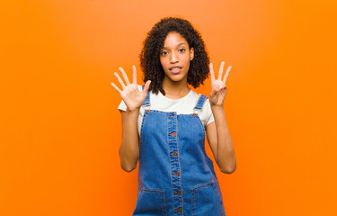 young pretty black woman smiling and looking friendly, showing number eight or eighth with hand...