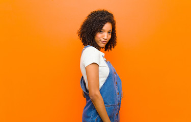 young pretty black woman looking proud, confident, cool, cheeky and arrogant, smiling, feeling...