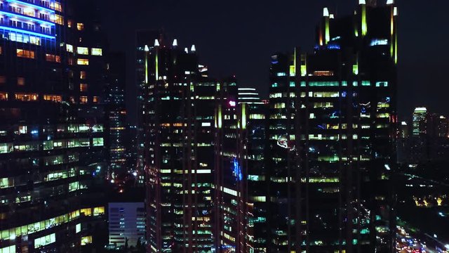 JAKARTA, Indonesia - October 07, 2019: Beautiful aerial scenery of modern office buildings exterior with night lights. Shot in 4k resolution from a drone flying forwards