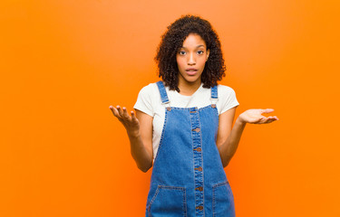 young pretty black woman open-mouthed and amazed, shocked and astonished with an unbelievable...