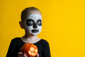 girl with pumpkin in hands in makeup halloween