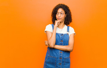 young pretty black woman thinking, feeling doubtful and confused, with different options, wondering...