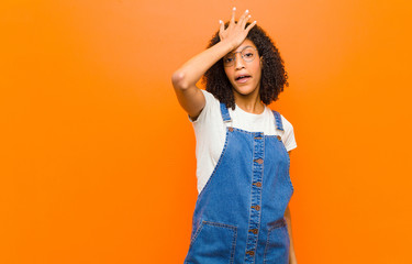 young pretty black woman raising palm to forehead thinking oops, after making a stupid mistake or...