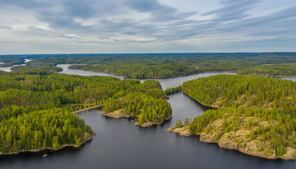 Aerial view of of small islands on a blue lake Saimaa. Landscape with drone. Blue lakes, islands and green forests from above on a cloudy summer morning. Lake landscape in Finland.
