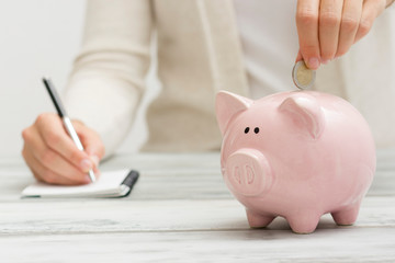 woman hand putting money coin into piggy for saving money wealth and financial concept