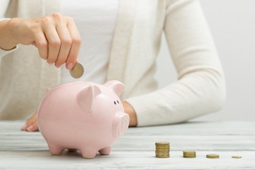 woman hand putting money coin into piggy for saving money wealth and financial concept.