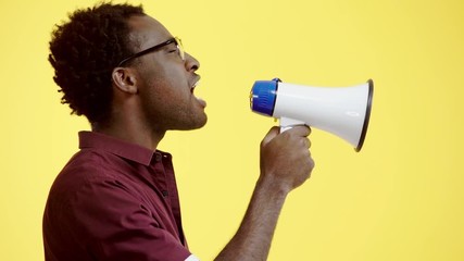 irritated african american man yelling into loudspeaker isolated on yellow - Powered by Adobe