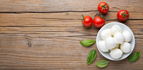 Small mozzarella balls, cherry tomatoes and basil. Top view, space for text. - obrazy, fototapety, plakaty