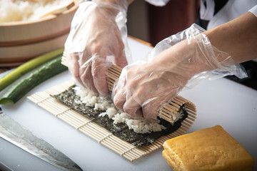 sushi chef making roll sushi with cucumber and egg