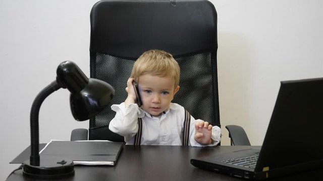 Funny baby child  talking on phone and navigate on internet, boy sit at business office