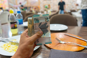 hand holding Banknotes of the Republic of Azerbaijan called Manat on a table of restaurant ready to pay
